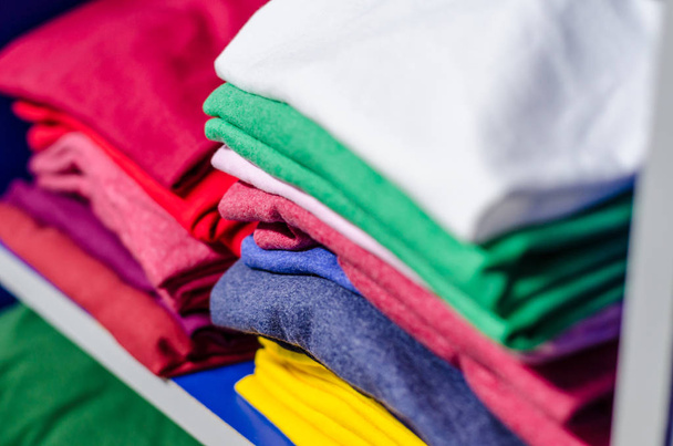 T-shirts made of multicolored fabric stacked in piles - 写真・画像