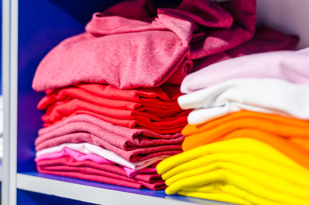 Camisetas de tela multicolor apiladas en pilas
 - Foto, Imagen