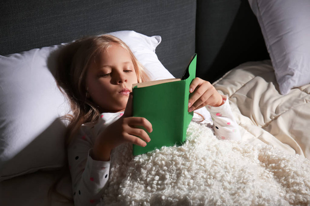 Sevimli küçük kız okuma kitabı evde yatakta - Fotoğraf, Görsel