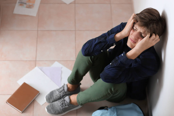 Adolescente triste sentado en el suelo en el interior. Acoso escolar
 - Foto, imagen