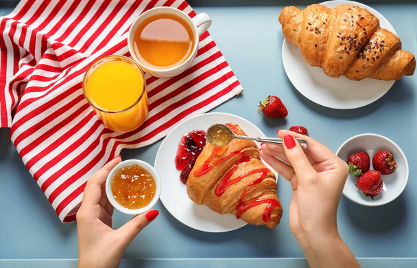 Young woman pouring tasty croissant with jam on plate - Photo, Image
