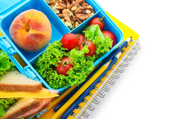 Boîte à lunch avec nourriture appétissante et papeterie sur fond blanc
 - Photo, image