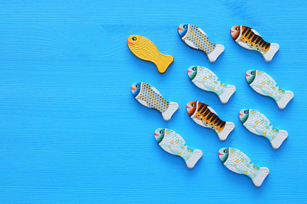 Leadership concept with swimming fish on wooden background. One leader leads others - Fotografie, Obrázek