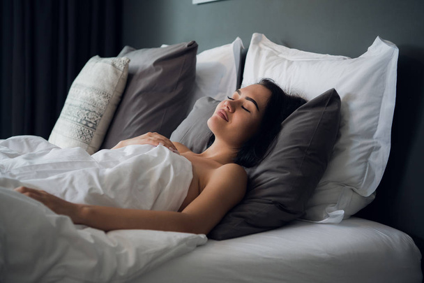 noche, descanso, comodidad y concepto de personas - mujer joven durmiendo en la cama en casa
 - Foto, Imagen