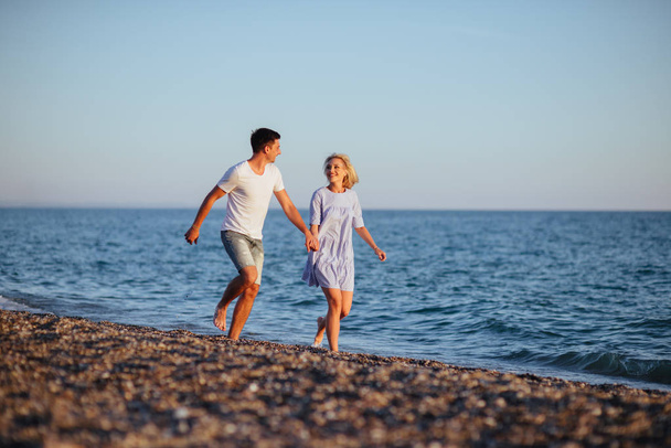 Young happy couple on beach near the sea at summer vacation - Фото, изображение