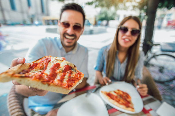 Casal comer pizza lanche ao ar livre. Eles estão compartilhando pizza e comer
. - Foto, Imagem
