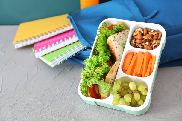 Caixa de almoço com comida apetitosa e saco na mesa
 - Foto, Imagem