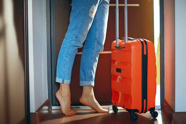 woman with a red suitcase leaves the room, the concept of tourism, departure - 写真・画像