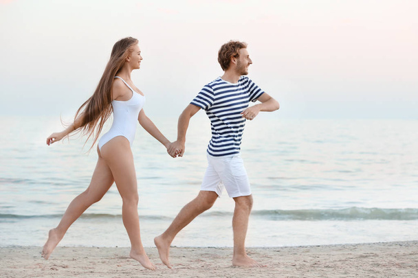 Happy young couple running on sea beach - Zdjęcie, obraz