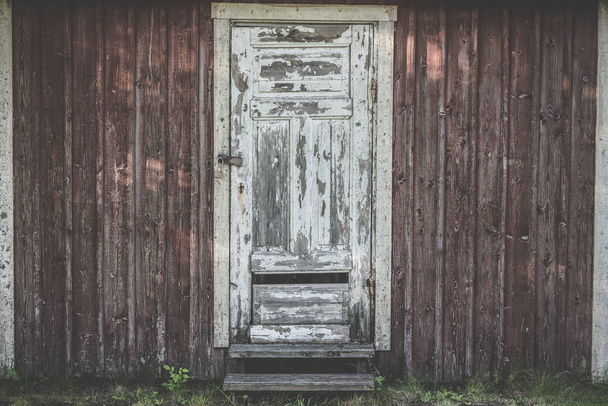 Old wooden door with weathered paint and torn planks with a lock - Foto, afbeelding