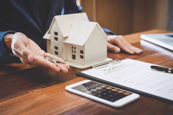 Менеджер з продажу нерухомості тримає ключі від клієнта після підписання договору оренди оренди договору купівлі-продажу щодо пропозиції іпотечного кредиту на страхування будинку
. - Фото, зображення