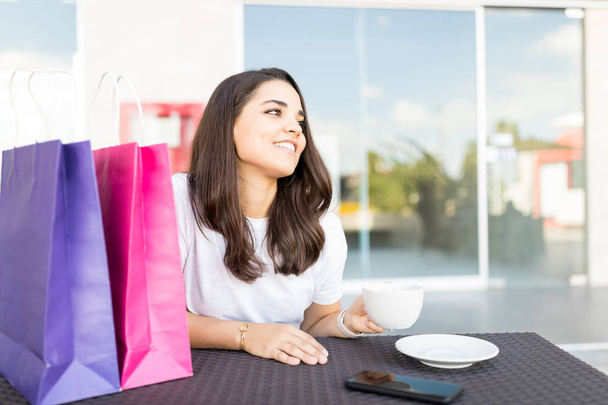 Sonriente mujer adulta medio tomando café después de ir de compras en el café en el centro comercial
 - Foto, imagen