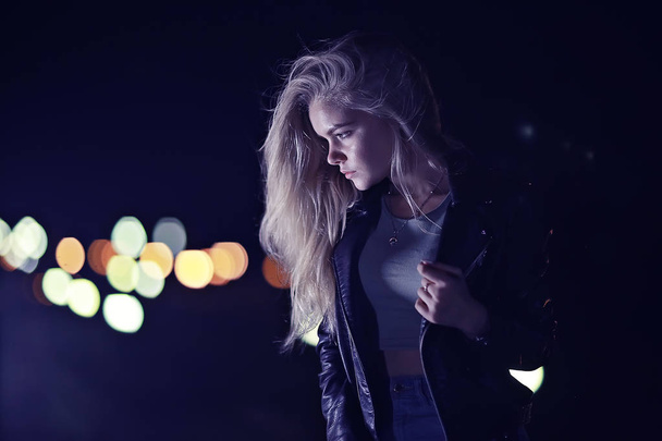 beautiful young woman with long hair posing at the city street at night - Фото, изображение