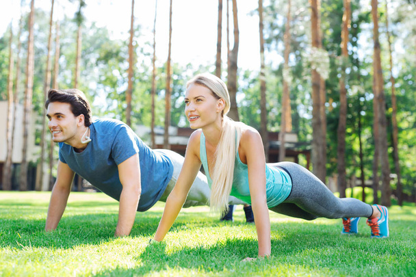 Delighted nice couple doing push ups together - Foto, imagen