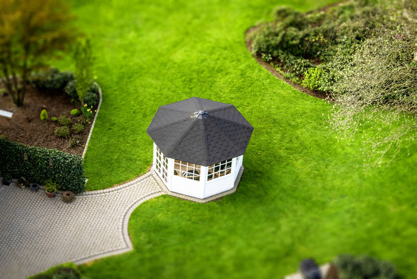 Pieni pavillon puutarhassa vihreällä nurmikolla keväällä ylhäältä katsottuna
 - Valokuva, kuva