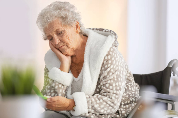 Disabled senior woman with medicine at home - Фото, изображение