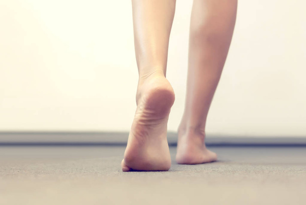 γυναικεία πόδια πάει σε ένα γκρι δάπεδο - Φωτογραφία, εικόνα