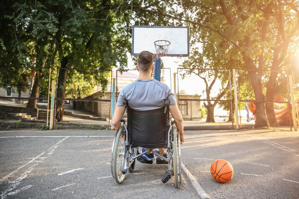 Mladý muž na vozíku hraje basketbal venku - Fotografie, Obrázek