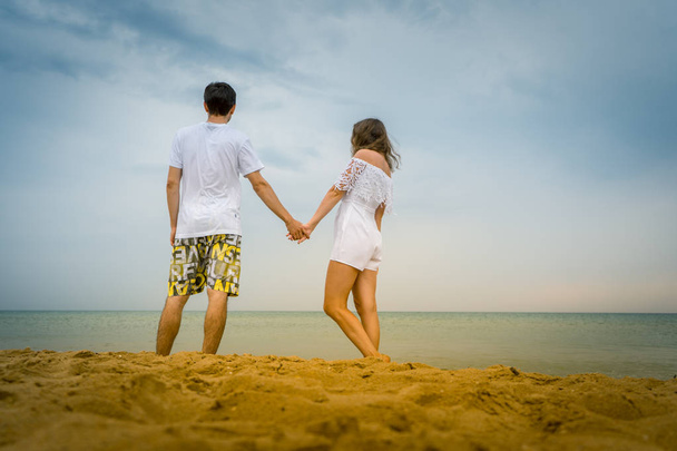 Glückliches Paar beim Spazierengehen am Strand oder Meer. Liebespaar spaziert an der Küste entlang. - Foto, Bild
