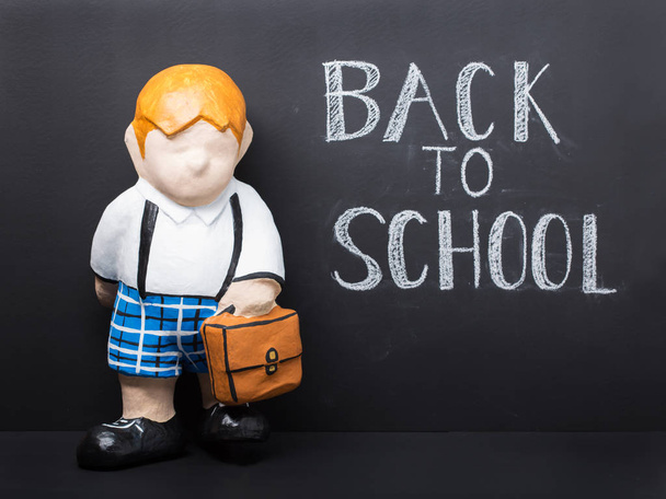 Back to school concept. Cute dummy with bag on black chalkboard background - Photo, Image