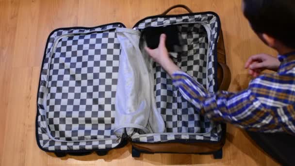 Reisekonzept von oben: Mann sortiert seine Kleidung und packt sie in Koffer - Filmmaterial, Video