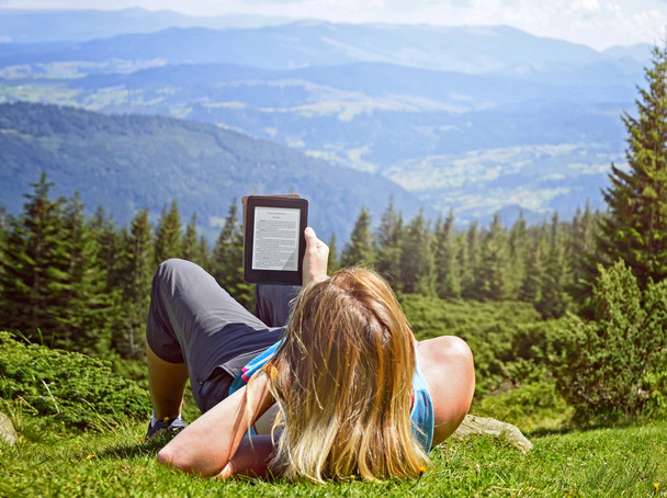 Nahaufnahme einer Frau, die E-Books in der Natur liest. Mädchen mit Tablet-Computer-Bildschirm, der editierbar ist isoliert auf Waldhintergrund in Dragobrat, Karpaten, Ukraine - Foto, Bild