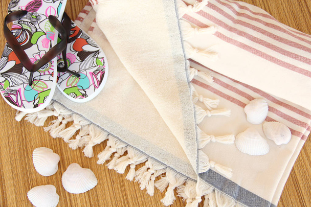 Tissu de plage en coton doux et luxueux avec des tongs à fleurs sur le tapis et les coquillages
 - Photo, image