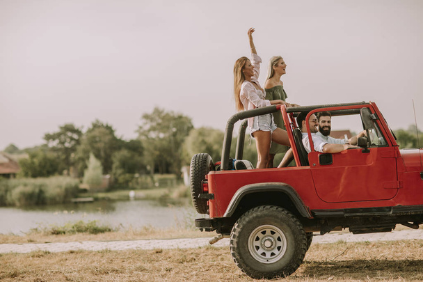 Mutlu arkadaşlar eğlenmeye Cabrio araba tatil nehir kenarında - Fotoğraf, Görsel