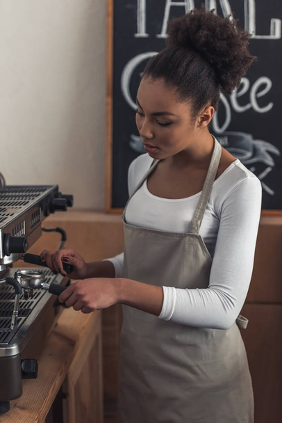 Szép Afro-amerikai barista kötény készül a kávé kávéfőző gépek használata - Fotó, kép