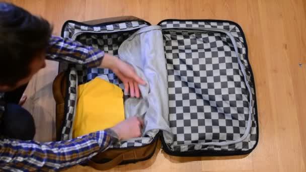 Üstten görünüm seyahat kavramı adam sıralama ve elbiselerini bavul paketleme - Video, Çekim