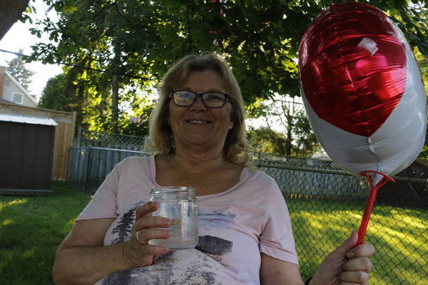 バック グラウンドでは、カナダの国旗を持って幸せな年上の女性 - 写真・画像