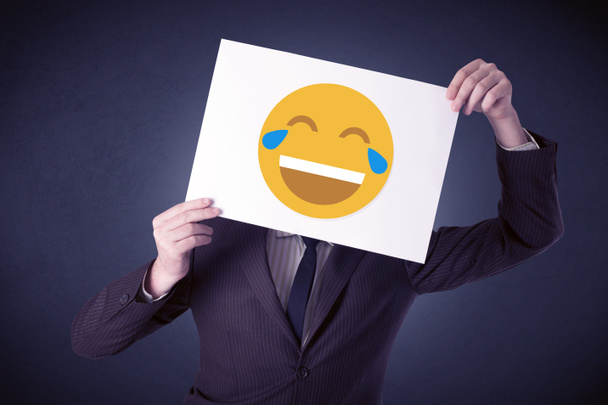 Бізнесмен тримає папір зі сміховинним емоційок
 - Фото, зображення