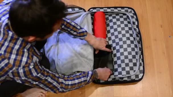 Bovenaanzicht reizen concept van man sorteren en verpakken van zijn kleren in koffer - Video