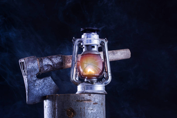 燃焼昔のガス灯と ax で木材のログと霧煙暗い夜背景。腐食防錆金属ランタン。ホラー ・ ハロウィンのコンセプト - 写真・画像