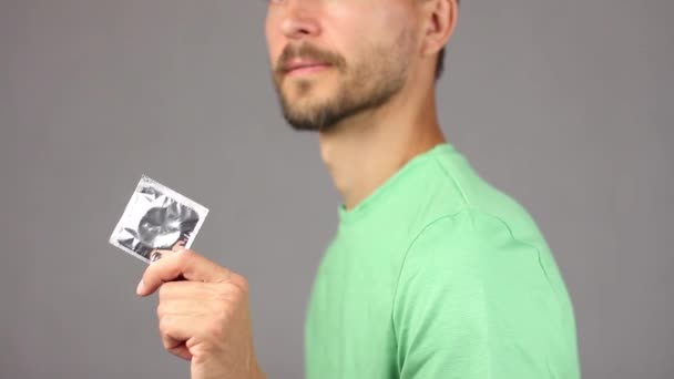людина з бородою і вусами тримає новий презерватив в руці і посміхається, концепція здорового способу життя і сексуальних відносин, сірий фон, портрет людини розмитий - не в фокусі, вид збоку
  - Кадри, відео