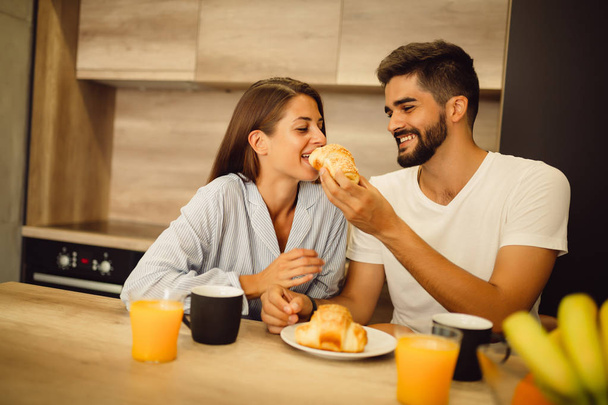 Heureux couple partageant leur petit déjeuner dans la cuisine le matin
 - Photo, image