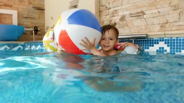 4k video de niño feliz lauhging en anillo inflable jugando con la madre y lanzando bola de playa colorida en la piscina
 - Metraje, vídeo