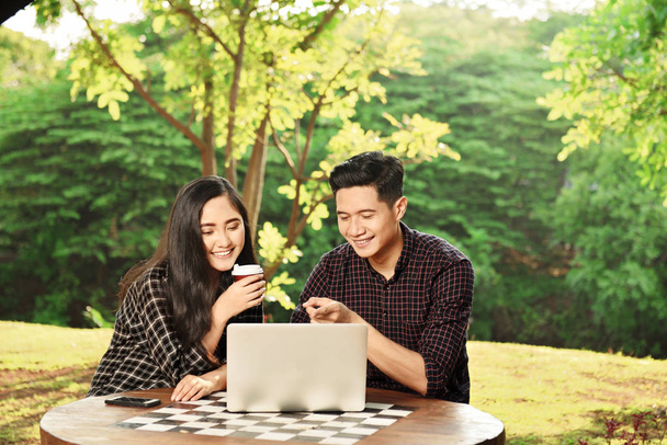 Happy asian couple with laptop on the park - Fotó, kép