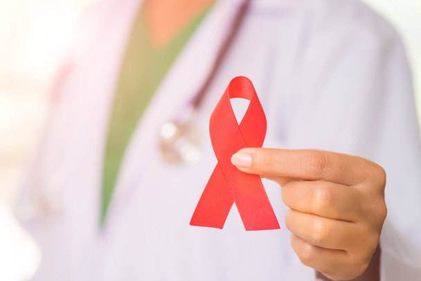 Médecine avec un stéthoscope à l'épaule portant le ruban rouge VIH, ruban de sensibilisation à la Journée mondiale du sida. Concept de santé et de médecine
. - Photo, image
