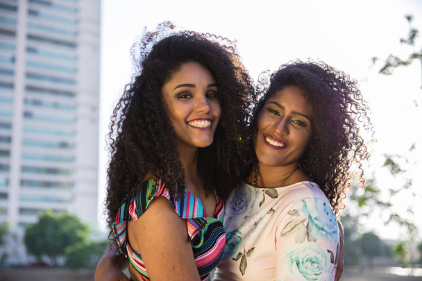 Két fiatal lány afro birtoklás móka együtt, öröm, pozitív, szeretet, barátság, Nővérek. Boldog találkozó a két baráti öleléssel. Leszbikus koncepció. - Fotó, kép