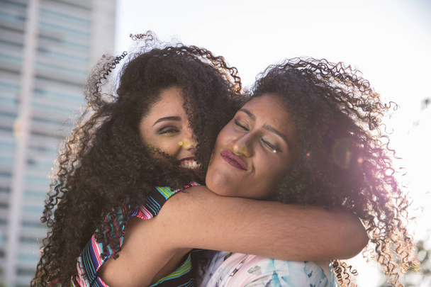 Dwie młode dziewczyny afro mając razem zabawa, radość, pozytywne, miłość, przyjaźń, siostry. Szczęśliwe spotkanie dwóch przyjaciół, przytulanie. Koncepcja lesbijka. - Zdjęcie, obraz