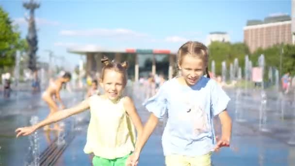 Urocze dziewczynki zabawy w ulicy fontanna w gorący słoneczny dzień - Materiał filmowy, wideo
