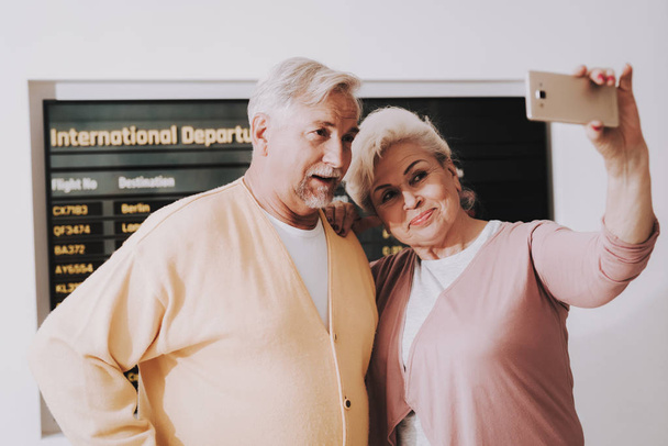 Old Couple Taking Photo in Airport in Waiting Room. Senior Person in Airport. Tourism Concept. Couple in Voyage. Airport Terminal. Vacation for Pensioner. People with Baggage. Travelers on Vacation. - Fotografie, Obrázek