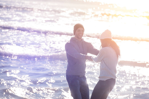 Молода пара весело гуляє і обіймається на пляжі під час осіннього сонячного дня
 - Фото, зображення