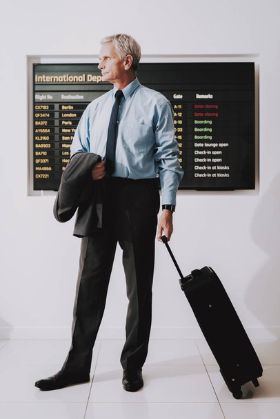 Man in Shirt with Bag in Airport in Waiting Room. Senior Person in Airport. Tourism Concepts. Businessman in Voyage. Shirt with Tie. Airport Terminal. Person with Baggage. Traveler on Vacation. - Foto, afbeelding