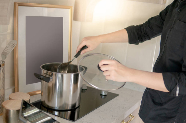 Męskiej ręki gotowanie garnek ze stali nierdzewnej lub garnek i chohcla na elektryczna piec w kuchni vintage. Przyrumienić w domu concept - Zdjęcie, obraz