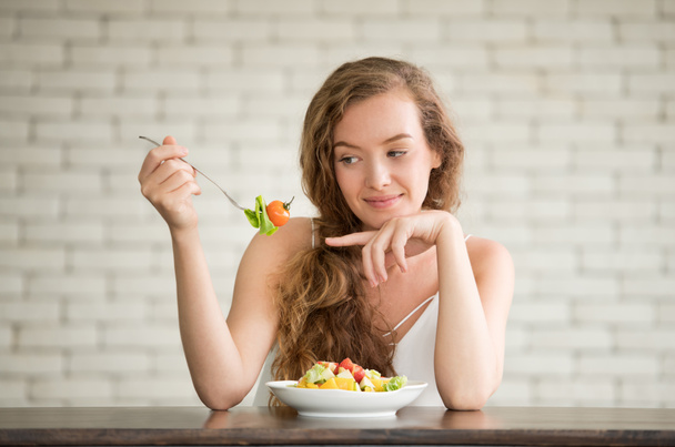 Beautiful young woman in joyful postures with salad bowl on the side - Photo, Image