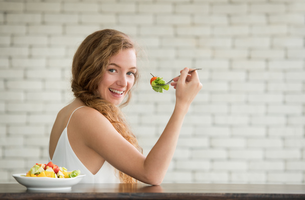 Gyönyörű fiatal nő, örömteli testhelyzetben saláta tál oldalán - Fotó, kép