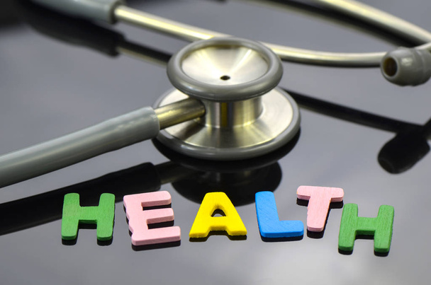 HEALTH letter with stethoscope on dark background. - Zdjęcie, obraz