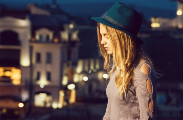 girl with hat in profile against night city background - Foto, imagen